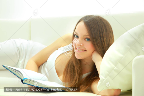 一位年輕女士躺在沙發(fā)上看書