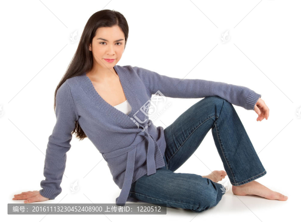 美麗的隨便打扮的女士坐在地板上，看著相機(jī)孤立的白色。