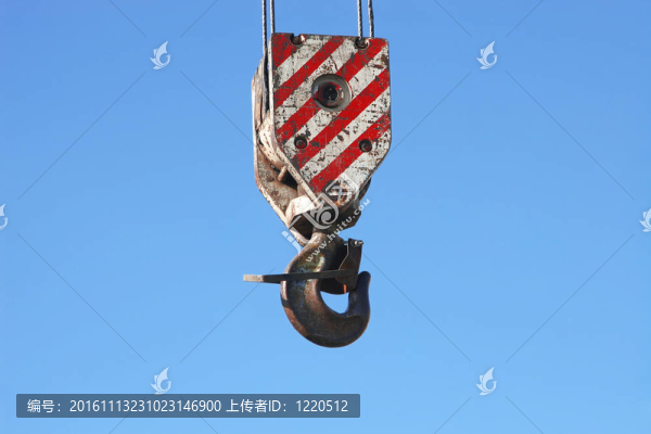 掛在藍天上的生銹的起重機吊鉤和鋼纜