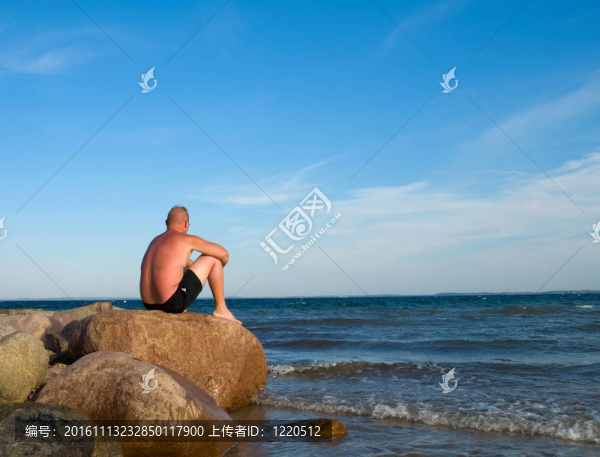 坐在石頭上的海海岸的人