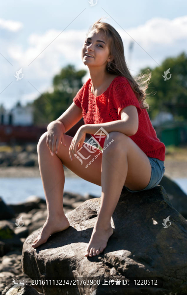 穿紅毛衣的女孩坐在巖石上