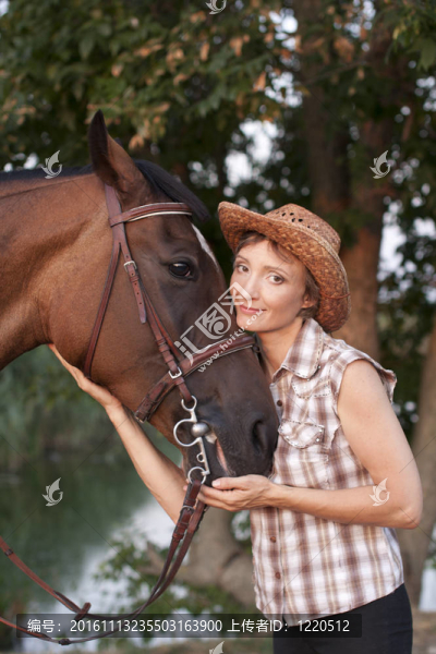 戴帽子的女人擁抱棕色的馬