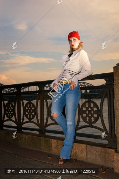 在落日的天空中的紅色的大手帕的年輕漂亮的女孩