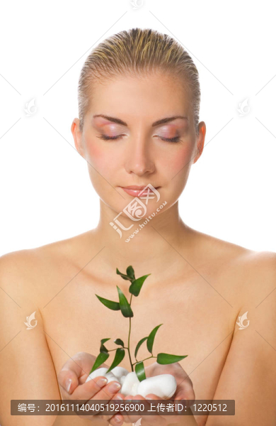 美麗的金發(fā)女孩抱著年輕的植物通過石頭長(zhǎng)大