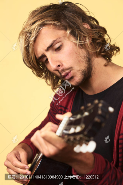 年輕英俊的白人男子彈吉他吹口哨（選擇性聚焦，專注于左眼）