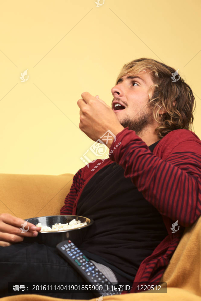 年輕人看電視和吃爆米花（選擇性聚焦，重點放在左邊的臉）