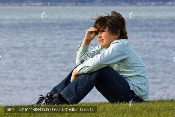 一個(gè)小男孩坐在海邊，看著遠(yuǎn)方