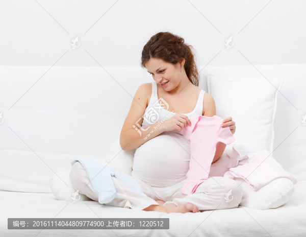 美麗的孕婦選擇嬰兒的衣服