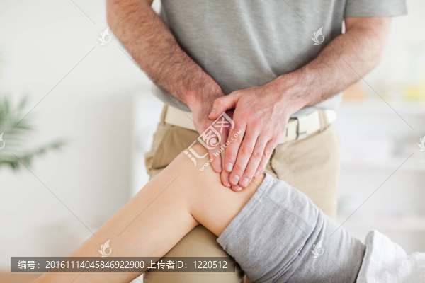 按摩師按摩一個迷人的女人的膝蓋