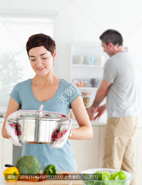可愛的妻子拿著鍋，而她丈夫正在洗碗