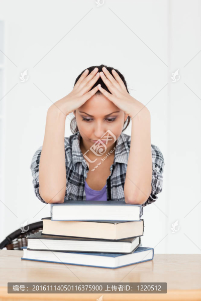 沮喪的年輕學生在書本上休息