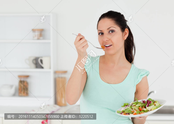 可愛的年輕女人在廚房里配沙拉