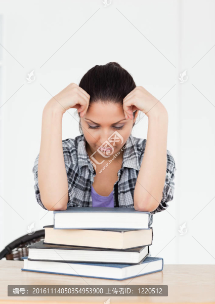 沮喪的年輕學生在書本上休息