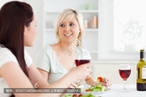 美女吃沙拉和喝葡萄酒的肖像