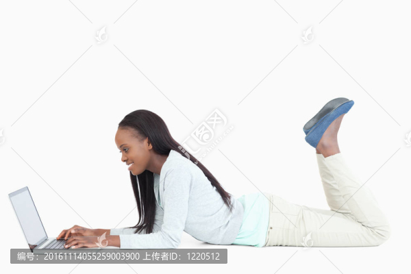 側(cè)面的女人躺在地板上與她的筆記本電腦