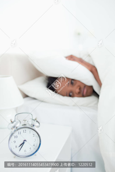 當(dāng)她的鬧鐘在臥室里響起時，一個疲倦的女人捂著她的耳朵