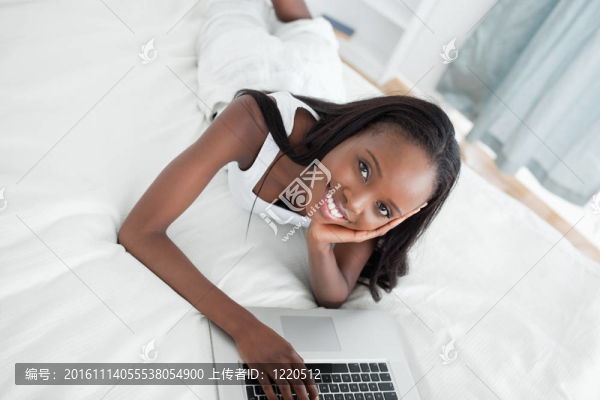 年輕女子趴在肚子上用筆記本