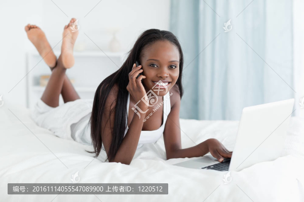 快樂女人在打電話時用筆記本