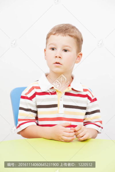 小男孩坐在一張桌子上