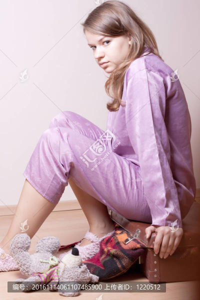穿著紫色睡衣的女孩坐在手提箱上