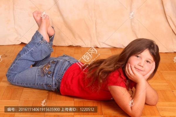 漂亮的小女孩躺在地板上穿著牛仔褲和襯衫