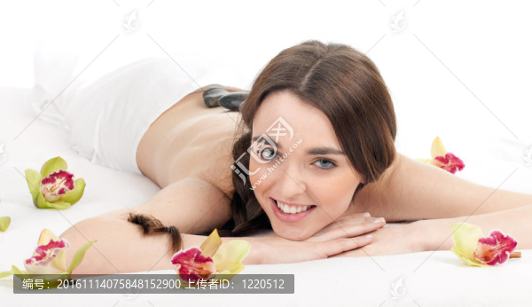 美麗的年輕女子在水療院；石頭按摩