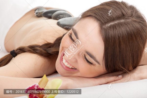美麗的年輕女子在水療院；石頭按摩