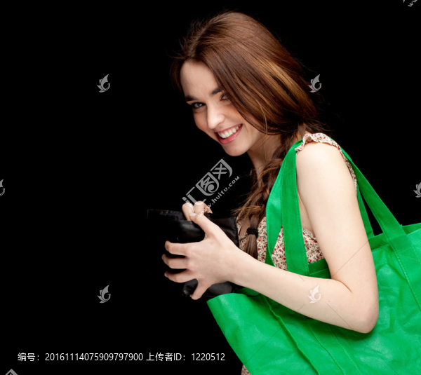 帶綠色生態(tài)購物袋的年輕女性；黑色背景