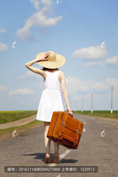 鄉(xiāng)村路上帶著手提箱的寂寞女孩。