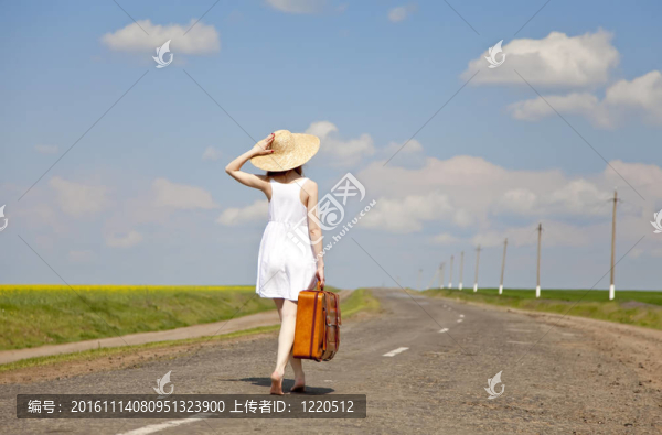 鄉(xiāng)村路上帶著手提箱的寂寞女孩。