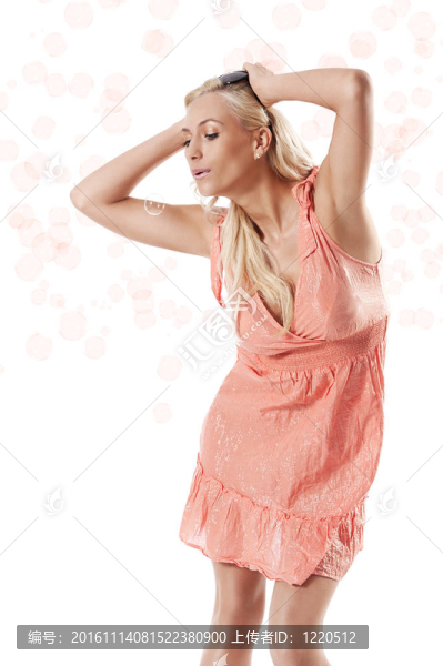 漂亮的年輕金發(fā)女人穿著夏天橙色的衣服站在白色的背景下玩肥皂泡