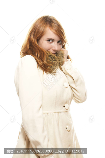 年輕的紅發(fā)女人捂著臉在小鹿的冬大衣在白色背景