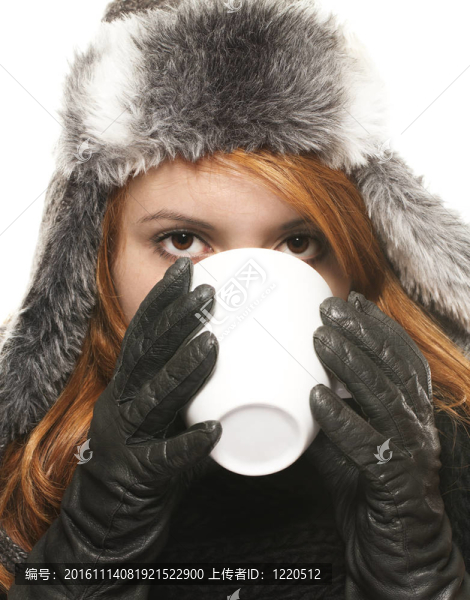 穿冬天衣服的年輕女子喝杯咖啡或茶