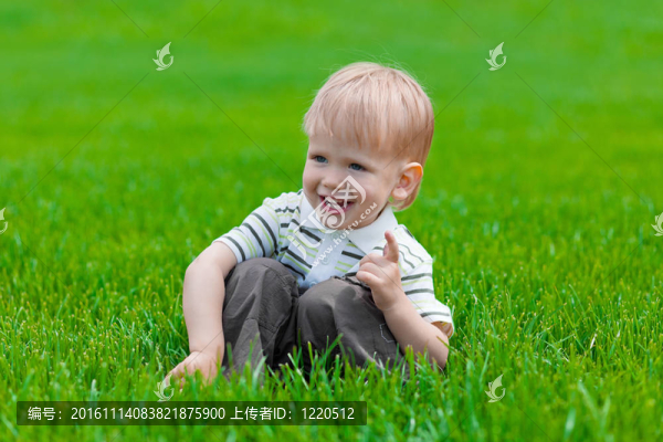 小男孩坐在綠色的草地上夢想
