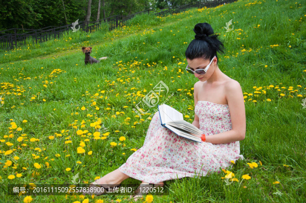 年輕的女人在公園里讀一本書