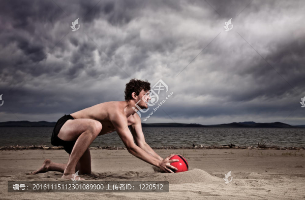 強(qiáng)性感男性與紅色球在海灘上