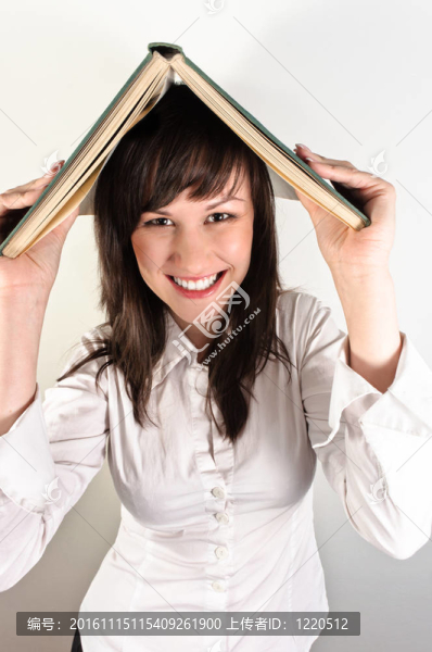 學生女孩拿著書在她的頭上