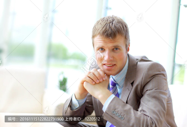 一位面帶微笑的年輕年輕商人坐在辦公椅上的畫像