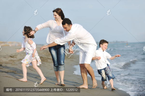 快樂的年輕家庭在海灘上玩得很開心