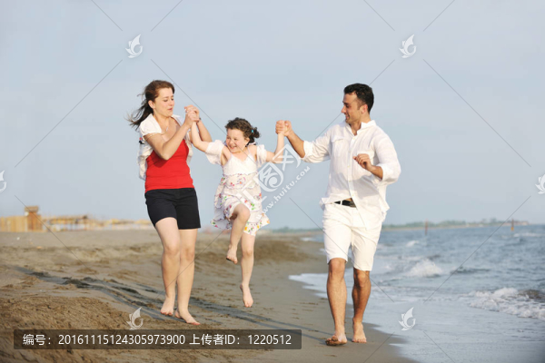 快樂的年輕家庭在海灘上玩得很開心