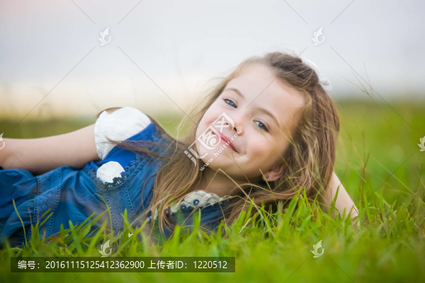 一個厚顏無恥的微笑在綠色的草地上放松的女孩