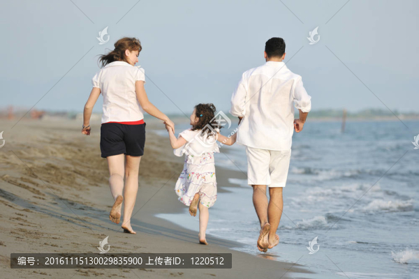 快樂的年輕家庭在海灘上玩得很開心