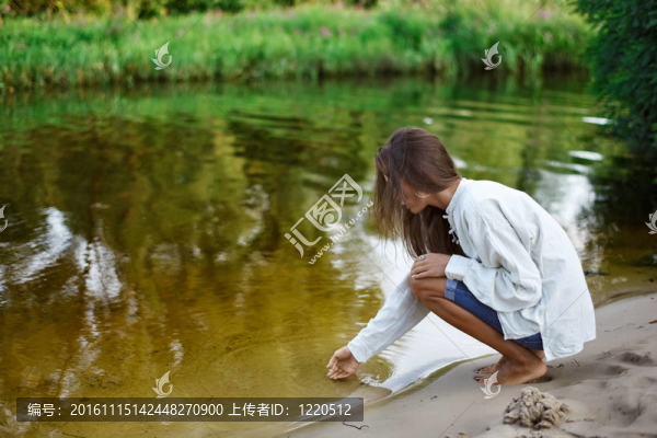 美麗的年輕女子在湖邊建沙堡