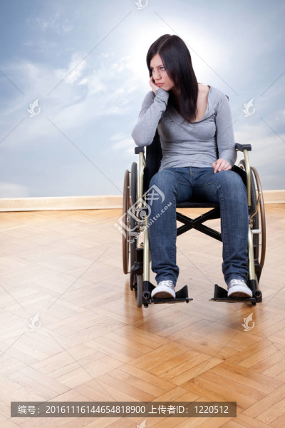 悲傷的年輕無效的女人坐在輪椅上