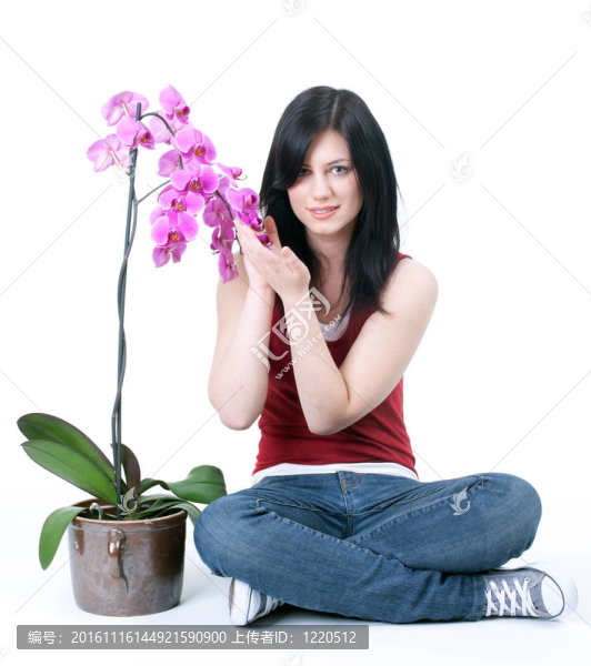 美麗的年輕女子與蘭花坐在地板上交叉雙腿