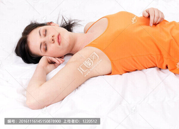 美麗的年輕女人睡在白色的被褥上