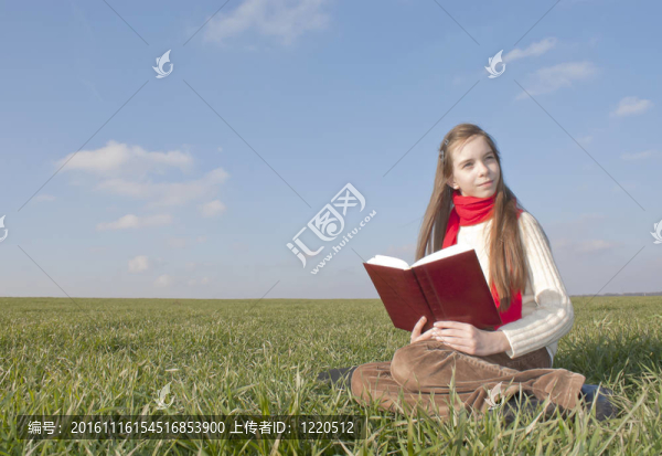 女孩在讀一本書坐在草地上