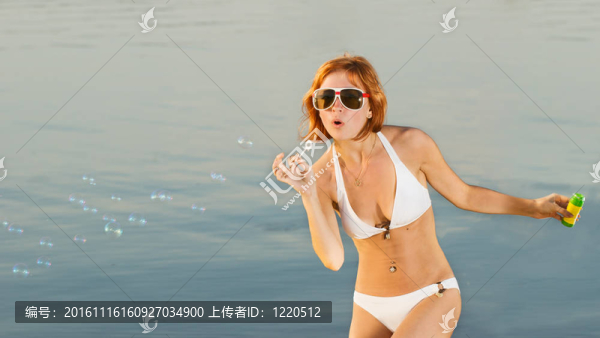 性感的女孩與肥皂泡沫在海灘上