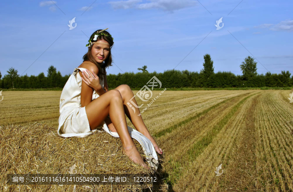 在一個(gè)鄉(xiāng)村的服裝坐在草堆里的女孩