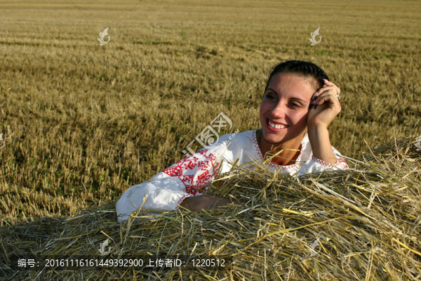 在傳統(tǒng)的俄羅斯服裝躺在干草堆里，微笑的女孩